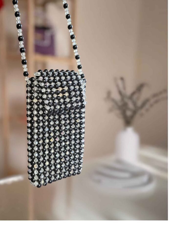striped with shiny transparent and black beaded handbag with chain strap .